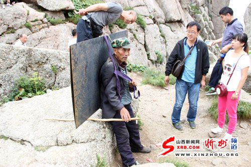 一位六十余岁的老者,为芦芽山景区建设背负上百斤的钢板行走山间
